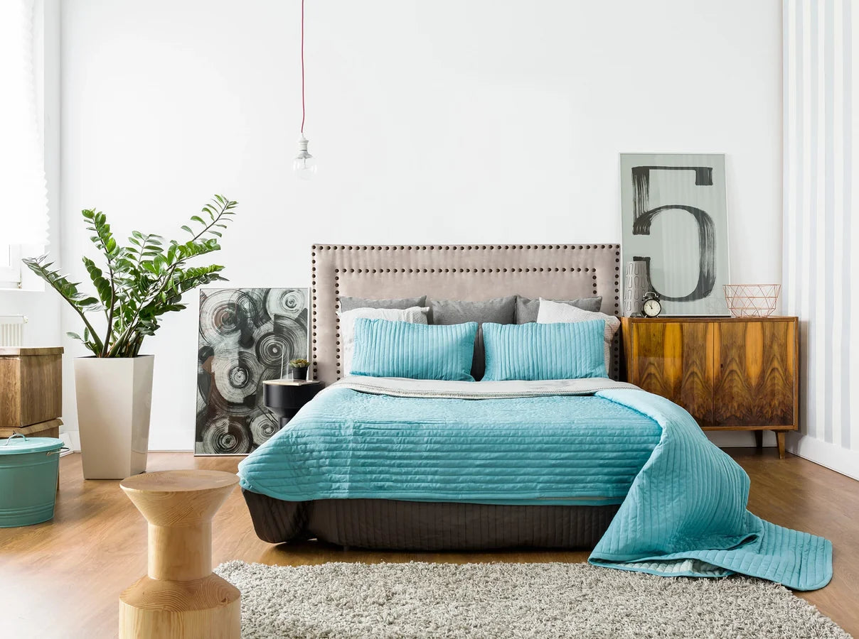 Mesa Auxiliar Macizo 06 en pino natural usada como mesilla junto a una cama, sobre suelo de madera