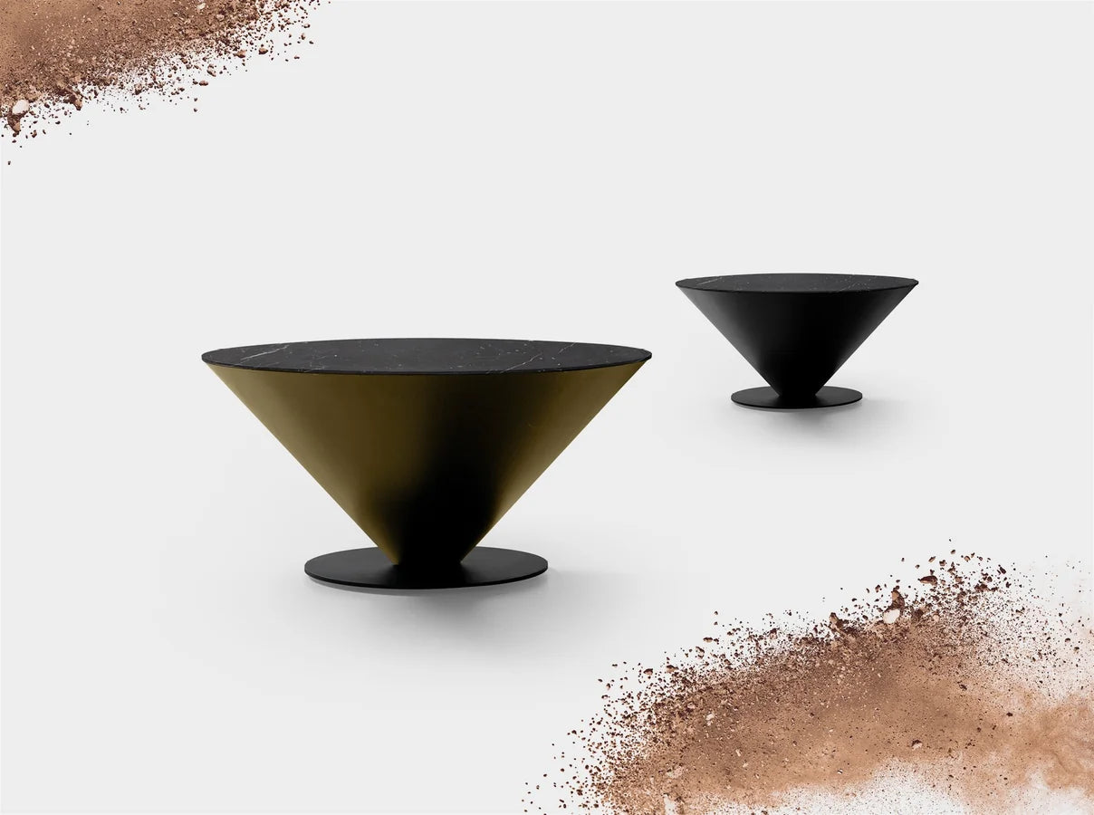 Dos mesas Peonza 03, una dorada y otra negra, en una composición con tierra de cacao