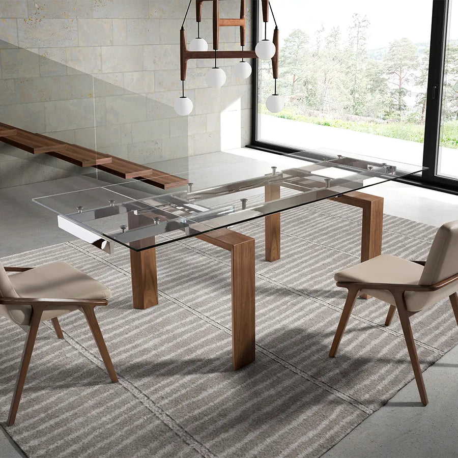 Mesa de Comedor Extensible 1007 en un comedor con ventanal, alfombra de rayas y butacas de nogal tapizadas en piel clara
