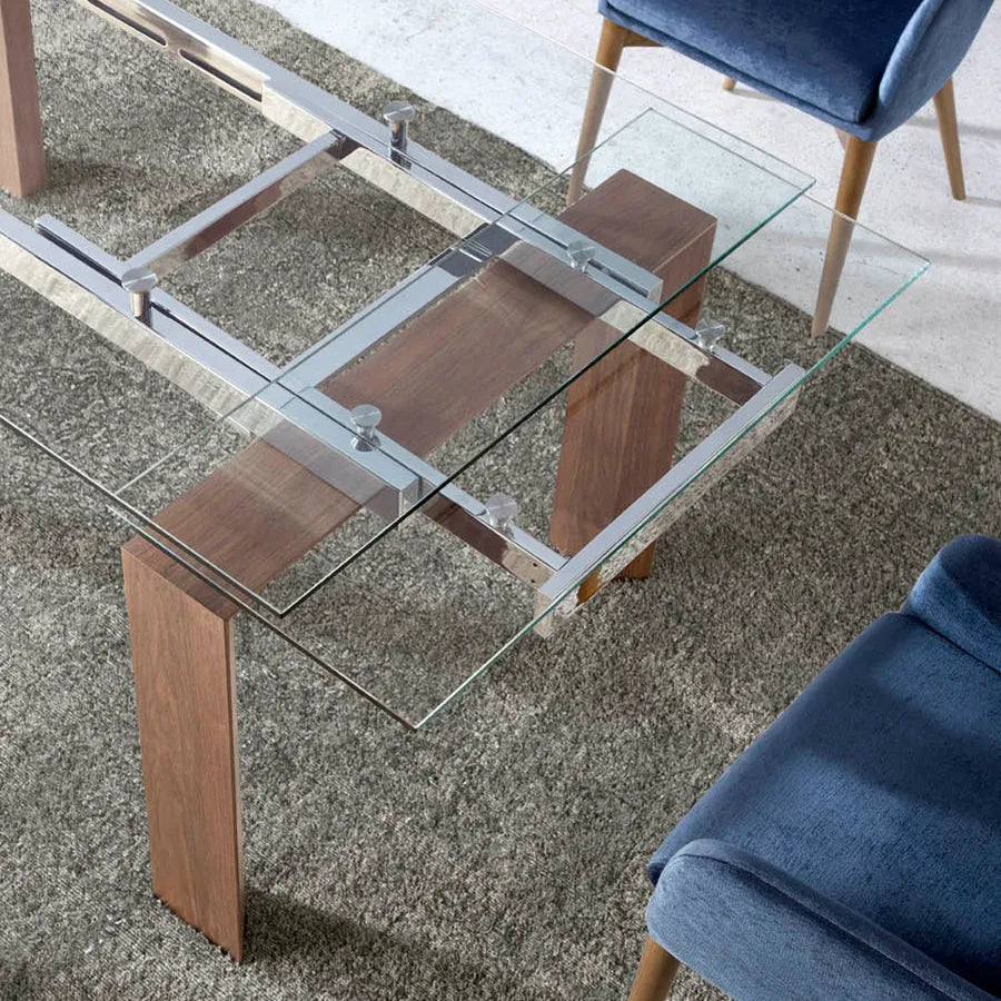 Detalle cenital de la Mesa 1007: el travesaño de nogal que une las patas y la estructura cromada vistos a través del cristal