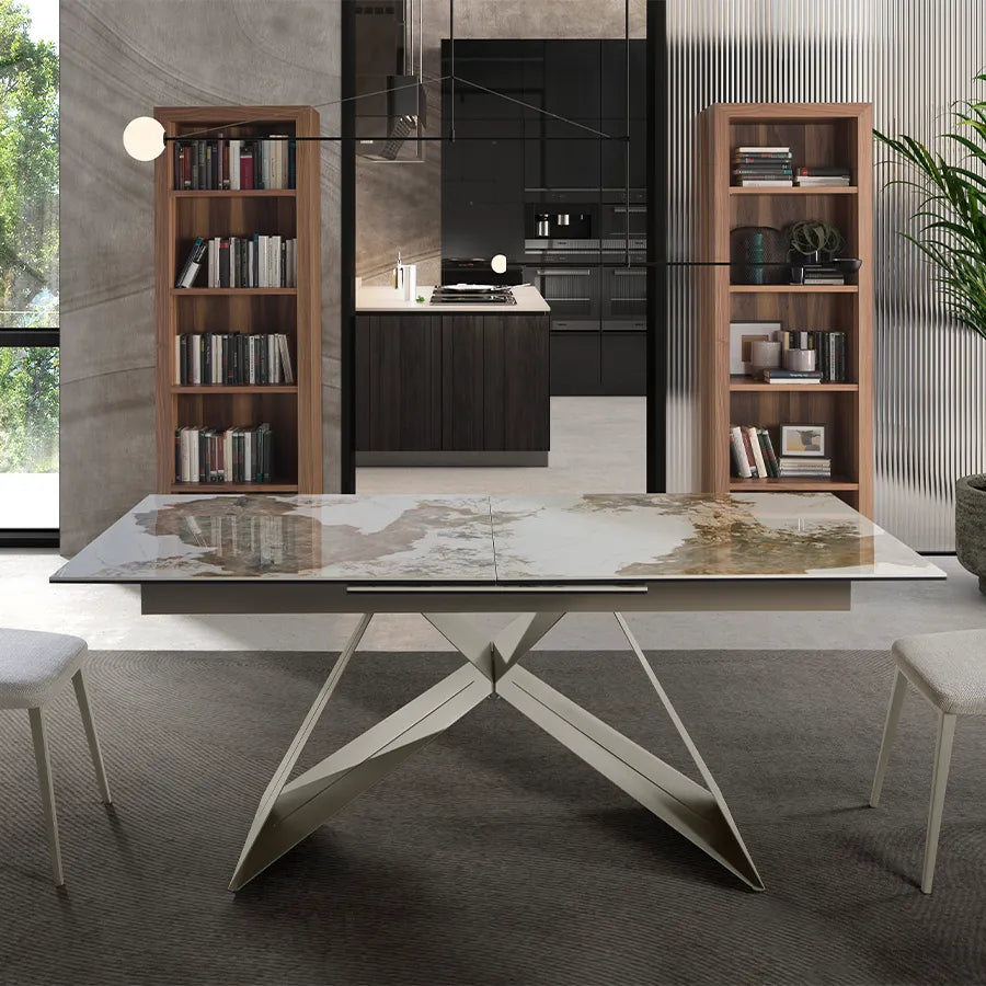 Mesa de Comedor Extensible 1114 cerrada en un comedor con cocina al fondo, estanterías de nogal y sillas tapizadas en tono crudo
