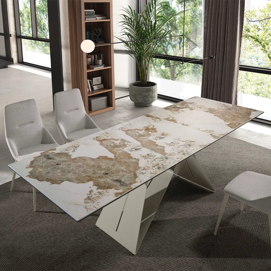 Mesa de Comedor Extensible 1114 extendida junto a un ventanal, rodeada de sillas tapizadas claras con patas de acero taupé