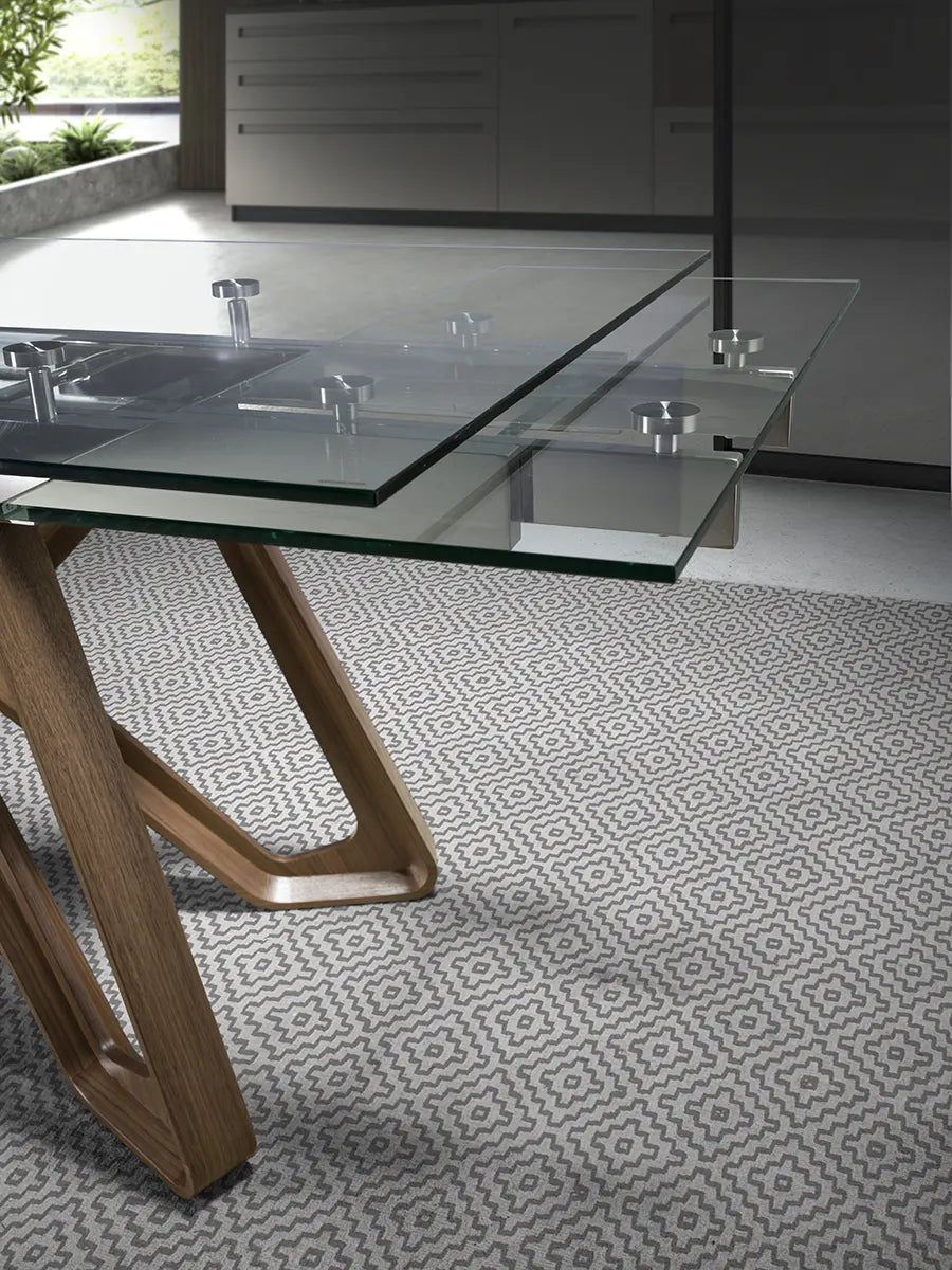 Detalle del ala extendida de la Mesa 1122, con el solape del cristal templado y sus herrajes sobre la pata de nogal