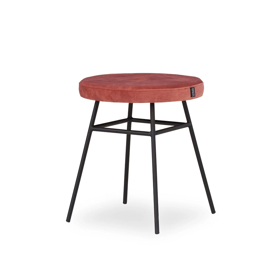 Puff Ainhoa de Casual Solutions tapizado en terracota, con asiento redondo y patas de metal lacado en negro, visto en tres cuartos